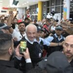 Graham Arnold embraced by jubilant Iraq supporters following World Cup qualification triumph.