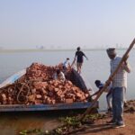 Transporting construction materials by boat: Singaporean group revitalizes flood-damaged homes in Indo-Pak border village.